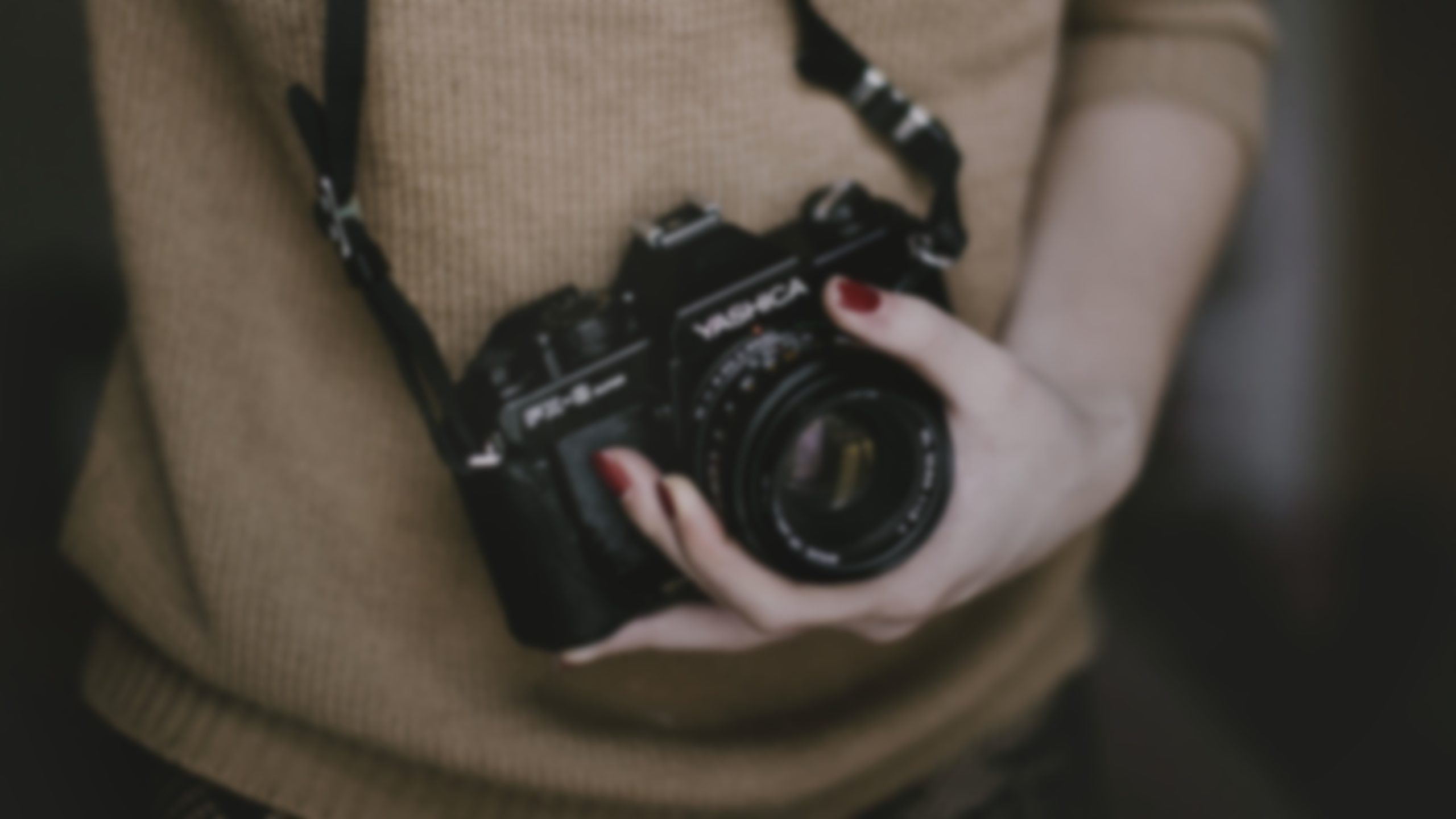 Female hand holding camera on top of a hat.