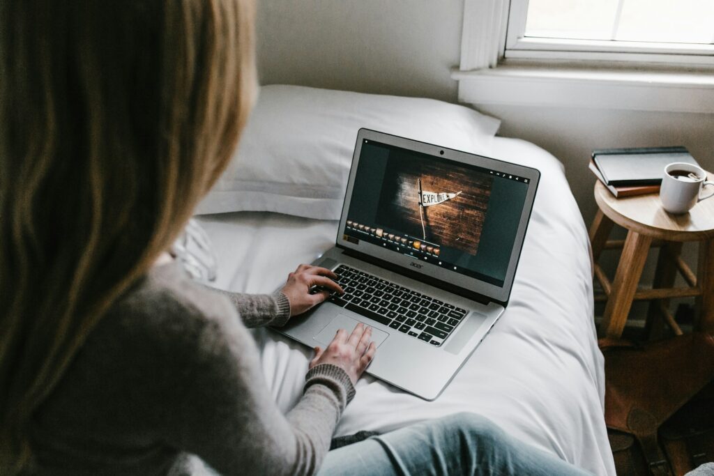 Girl looking at computer while sitting on bed.